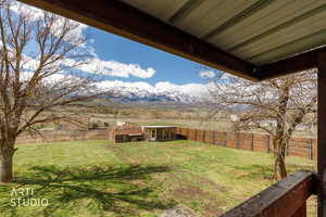 Fenced backyard featuring a mountain view, an outdoor structure, and a patio area