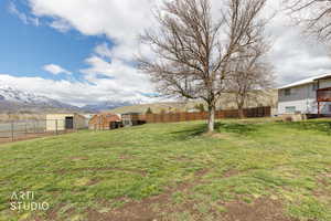 Fenced backyard with an outdoor structure, a mountain view, and exterior structure