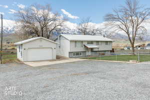 Split foyer home with a mountain view, an outbuilding, a detached garage, a metal roof, and concrete and gravel driveway