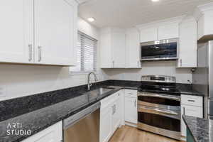 Kitchen featuring stainless steel appliances, white cabinetry, dark stone counters, a textured ceiling, and recessed lighting