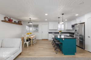 Kitchen with a center island, stainless steel appliances, dual tone cabinetry, a breakfast bar area, and light wood-style floors