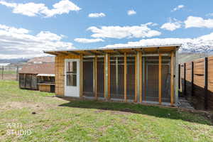 Back of property featuring a mountain view, an outbuilding, and a sunroom