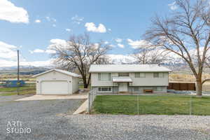 Raised ranch with a mountain view, a garage, an outbuilding, and a fenced front yard