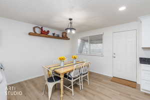Dining space with light wood-style flooring and a textured ceiling