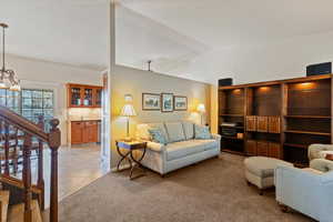 Living area featuring vaulted ceiling, light carpet, and light tile patterned floors