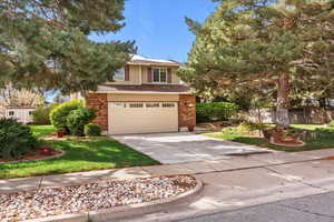 View of front of house featuring concrete driveway, a garage, brick siding, and a shingled roof