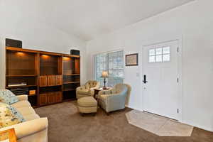 Living area featuring carpet and vaulted ceiling