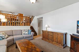 Carpeted living area with a ceiling fan and a textured ceiling