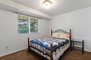 Bedroom with dark carpet and a textured ceiling