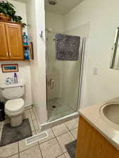 Bathroom featuring vanity, a shower stall, and light tile patterned floors