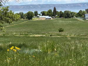 View of green lawn with a view of rural / pastoral area and a water and mountain view