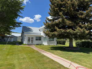 View of front of house featuring french doors, a front lawn, and a metal roof