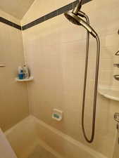 Bathroom featuring bathing tub / shower combination and vaulted ceiling