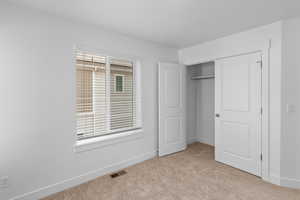 Unfurnished bedroom featuring light colored carpet and a closet