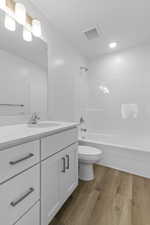 Full bath with vanity, dark wood-style floors, and washtub / shower combination