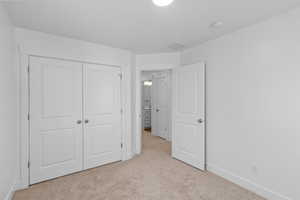 Unfurnished bedroom with light colored carpet and a closet