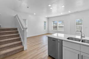 Kitchen featuring stainless steel dishwasher, light wood-style flooring, light stone counters, recessed lighting, and open floor plan