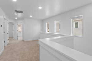 Hallway featuring an upstairs landing, recessed lighting, light carpet, and a textured ceiling