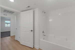 Bathroom featuring washtub / shower combination and light wood-style floors