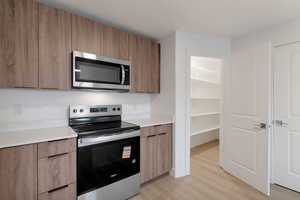 Kitchen featuring stainless steel appliances, modern cabinets, light wood-type flooring, and wood finish cabinetry