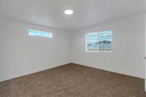 Unfurnished room featuring dark colored carpet and baseboards