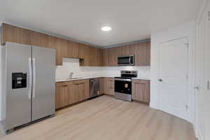 Kitchen featuring stainless steel appliances, light countertops, light wood-type flooring, modern cabinets, and recessed lighting