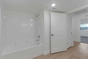 Bathroom with shower / washtub combination and light wood finished floors