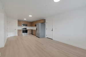 Kitchen featuring modern cabinets, stainless steel appliances, light countertops, light wood-type flooring, and wood finish cabinetry
