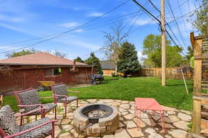 Fenced backyard with a patio area, an outdoor fire pit, and grilling area