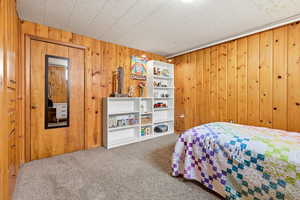 Bedroom with carpet flooring and wood walls