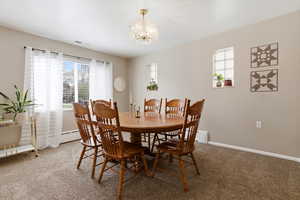 Dining room featuring carpet flooring, plenty of natural light, and a chandelier