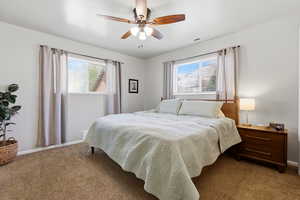 Bedroom featuring a ceiling fan and dark carpet