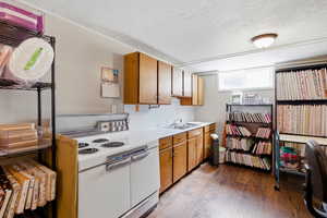 Kitchen with double oven range, light countertops, wood finish cabinetry, a textured ceiling, and light wood finished floors