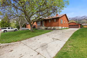 View of front of home featuring a mountain view, a garage, a chimney, and a front lawn