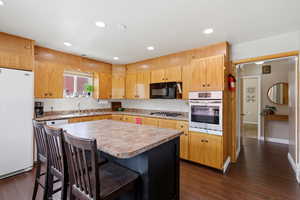 Kitchen with light countertops, stainless steel appliances, a kitchen bar, a kitchen island, and recessed lighting