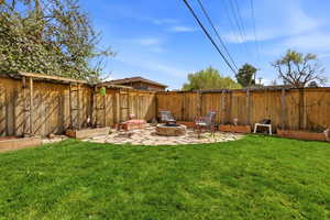 Fenced backyard featuring a patio area and a fire pit