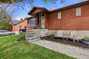View of exterior entry with a lawn and brick siding