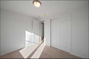 Unfurnished bedroom featuring light colored carpet and a closet