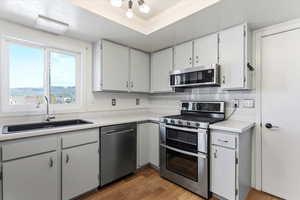 Kitchen featuring stainless steel appliances, light countertops, dark wood-type flooring, a textured ceiling, and backsplash