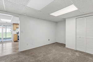 Below grade area with a paneled ceiling and dark carpet