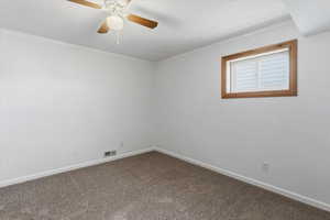 Spare room with ornamental molding, dark colored carpet, and ceiling fan