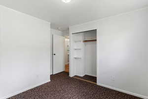 Unfurnished bedroom featuring crown molding, a closet, and dark carpet