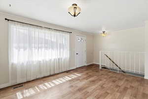 Unfurnished room featuring light wood finished floors, ornamental molding, and a textured ceiling