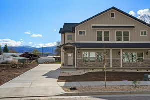 View of front of home featuring a porch, roof with shingles, board and batten siding, a mountain view, and stone siding