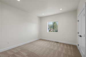 Unfurnished bedroom with a closet, light carpet, and recessed lighting