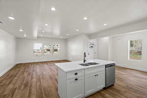 Kitchen featuring open floor plan, light wood-style floors, an island with sink, stainless steel dishwasher, and recessed lighting