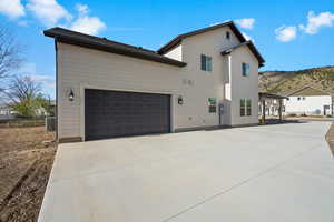 View of side of property with driveway, a mountain view, and a garage