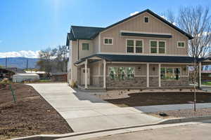 Craftsman inspired home featuring a porch, a mountain view, driveway, roof with shingles, and board and batten siding