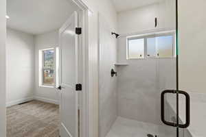 Bathroom with a shower stall, healthy amount of natural light, and light colored carpet
