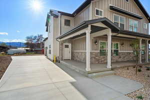 View of front of home with a porch, board and batten siding, stone siding, and concrete driveway